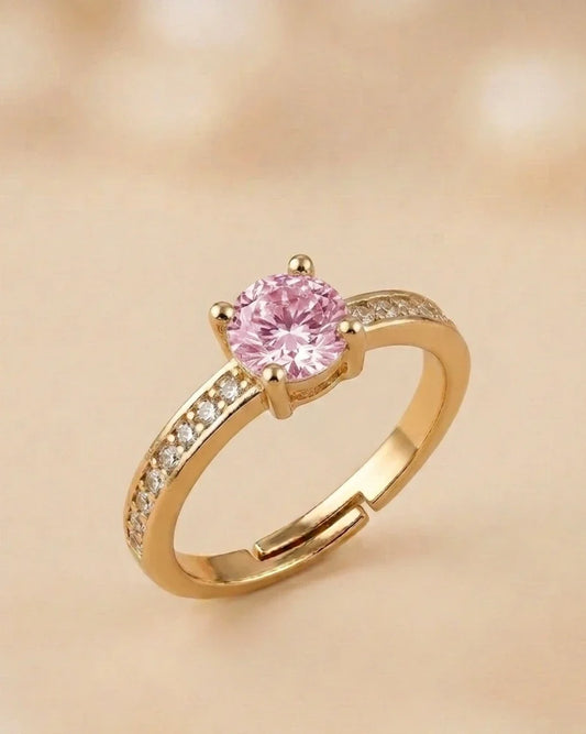 Gold ring with a pink gemstone on a beige background