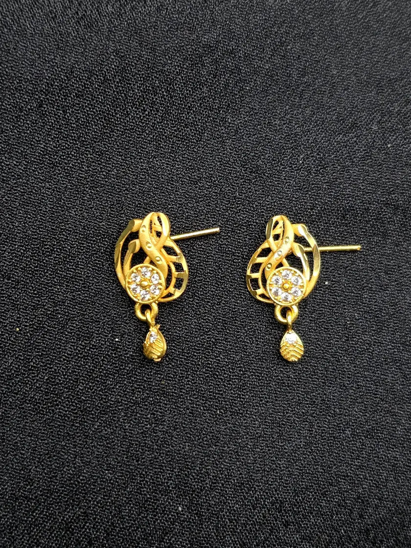 Gold earrings with intricate designs on a black background