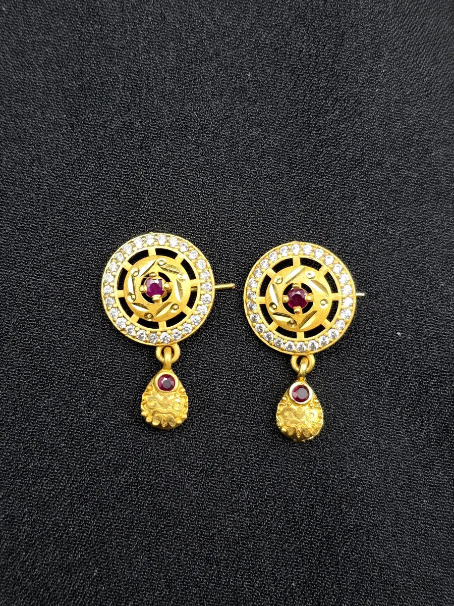 Gold earrings with red gemstones on a black background