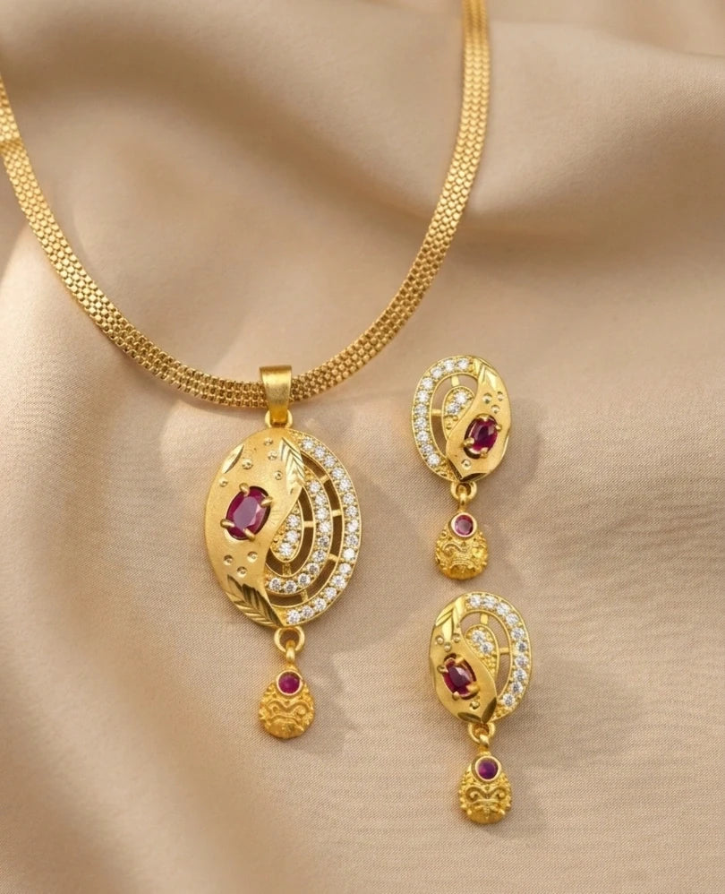 Gold necklace and earrings set with red gemstones on a beige fabric background