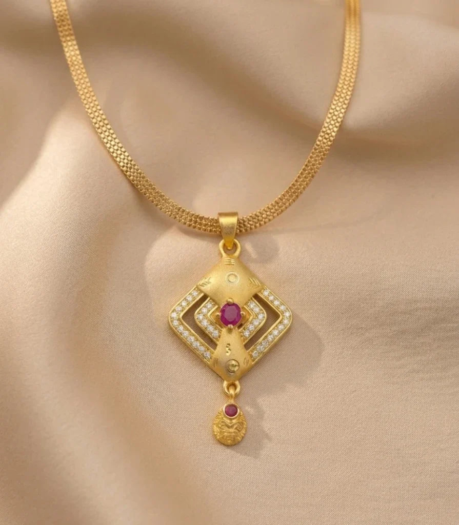 Gold necklace with a diamond-shaped pendant on a beige fabric background