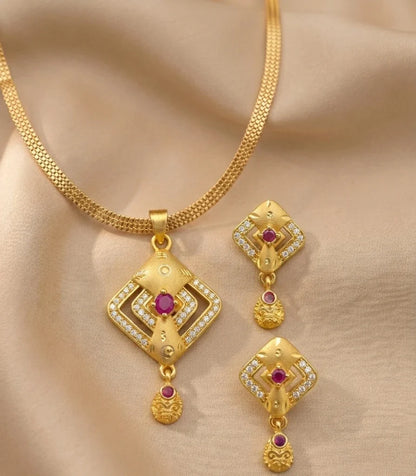 Gold necklace and earrings set on a beige fabric background