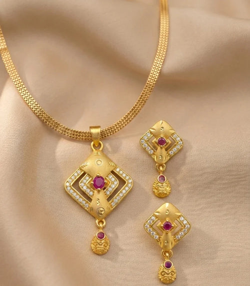 Gold necklace and earrings set on a beige fabric background