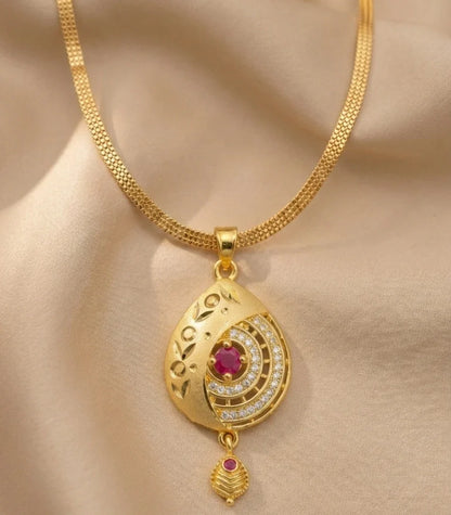 Gold necklace with a detailed pendant on a beige fabric background