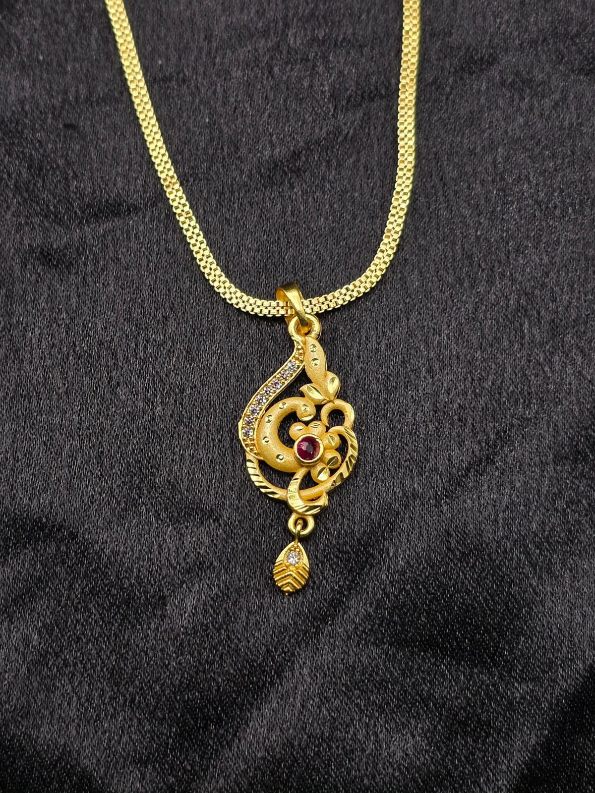 Gold necklace with a decorative pendant on a black fabric background