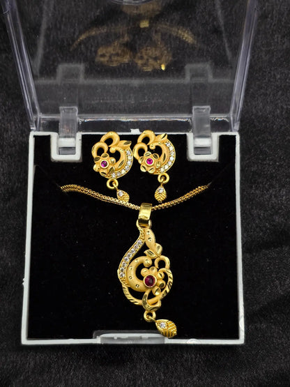 Gold necklace and earrings set in a clear box on a black background