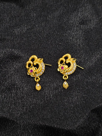Pair of gold earrings with floral design and red gemstones on a black background