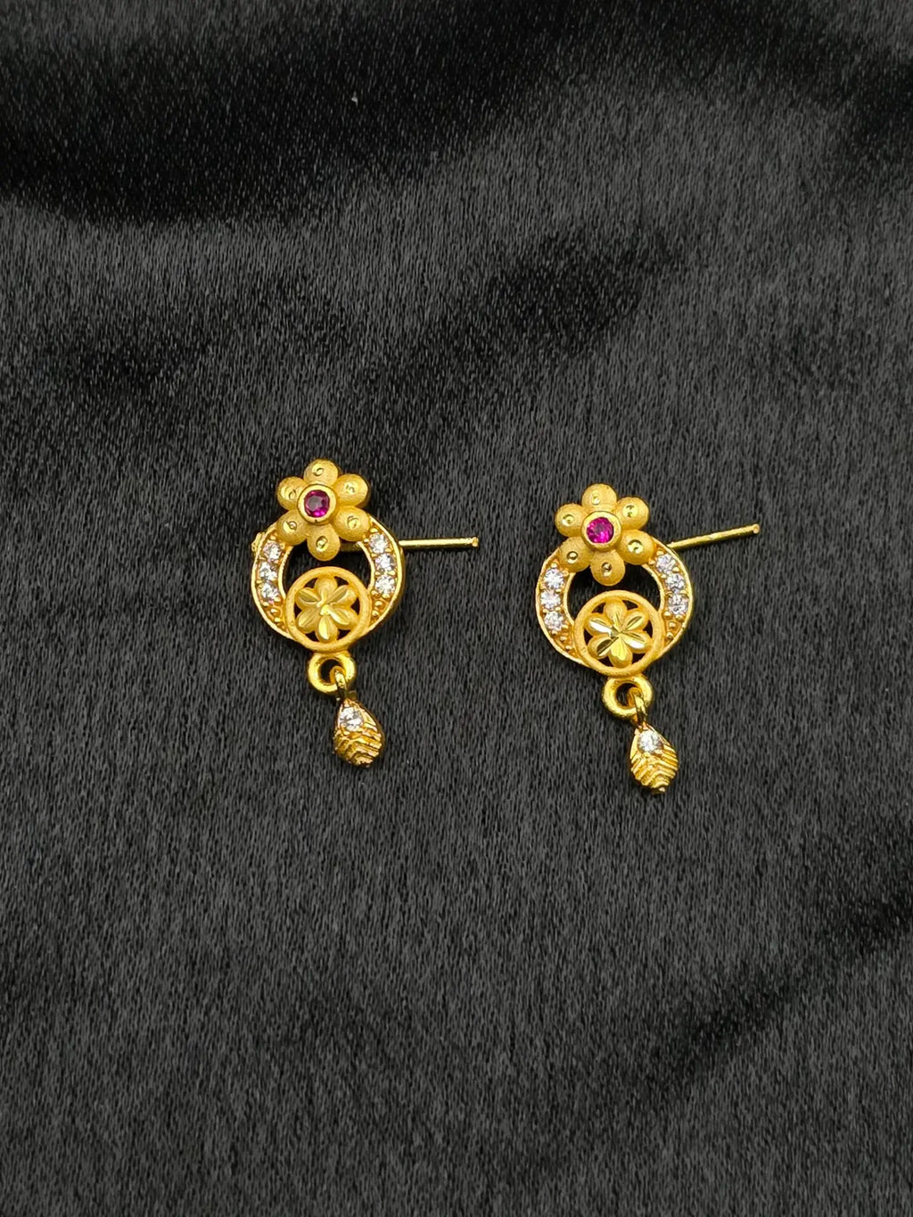 Pair of gold earrings with gemstones on a black background