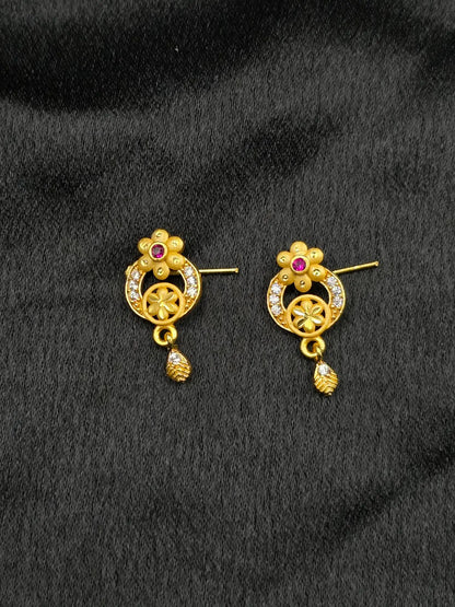 Pair of gold earrings with gemstones on a black background