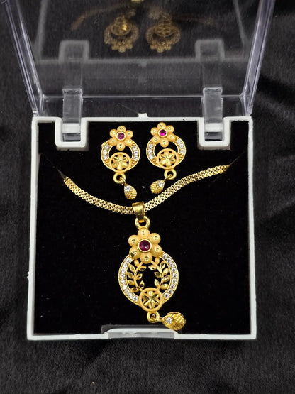 Gold necklace and earrings set in a clear display case on a black background