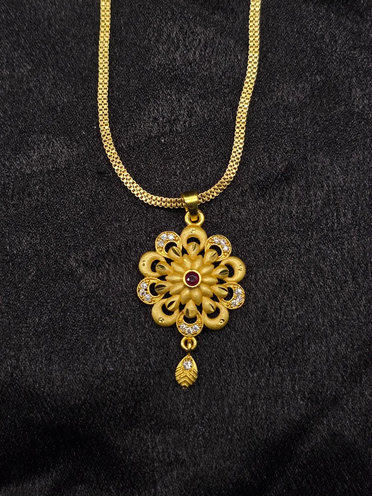Gold necklace with a floral pendant on a black background