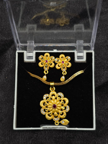 Gold necklace and earrings set in a clear display case on a black background