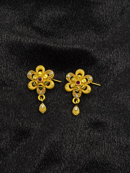 Pair of gold floral earrings with gemstones on a black background
