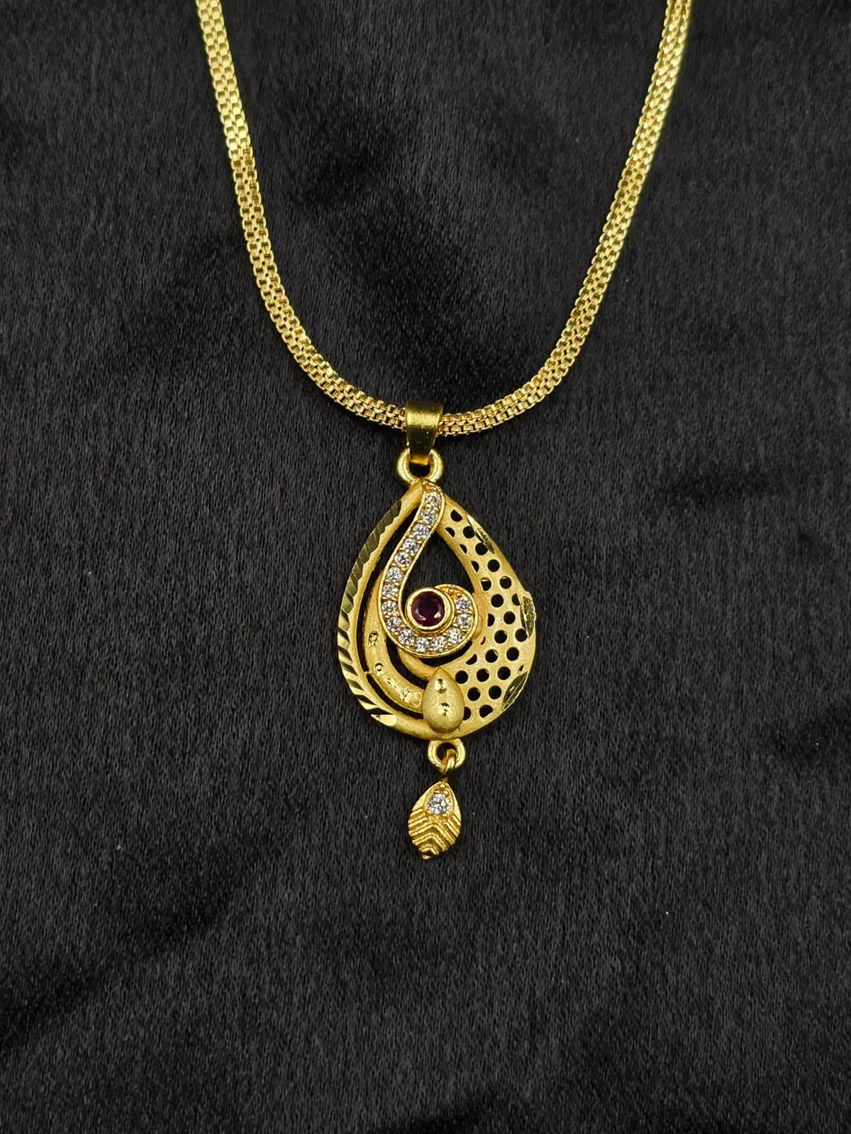 Gold necklace with a pendant on a black fabric background