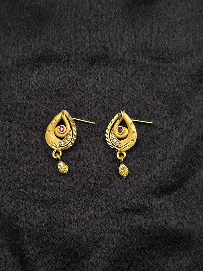 Gold earrings with gemstones on a black fabric background