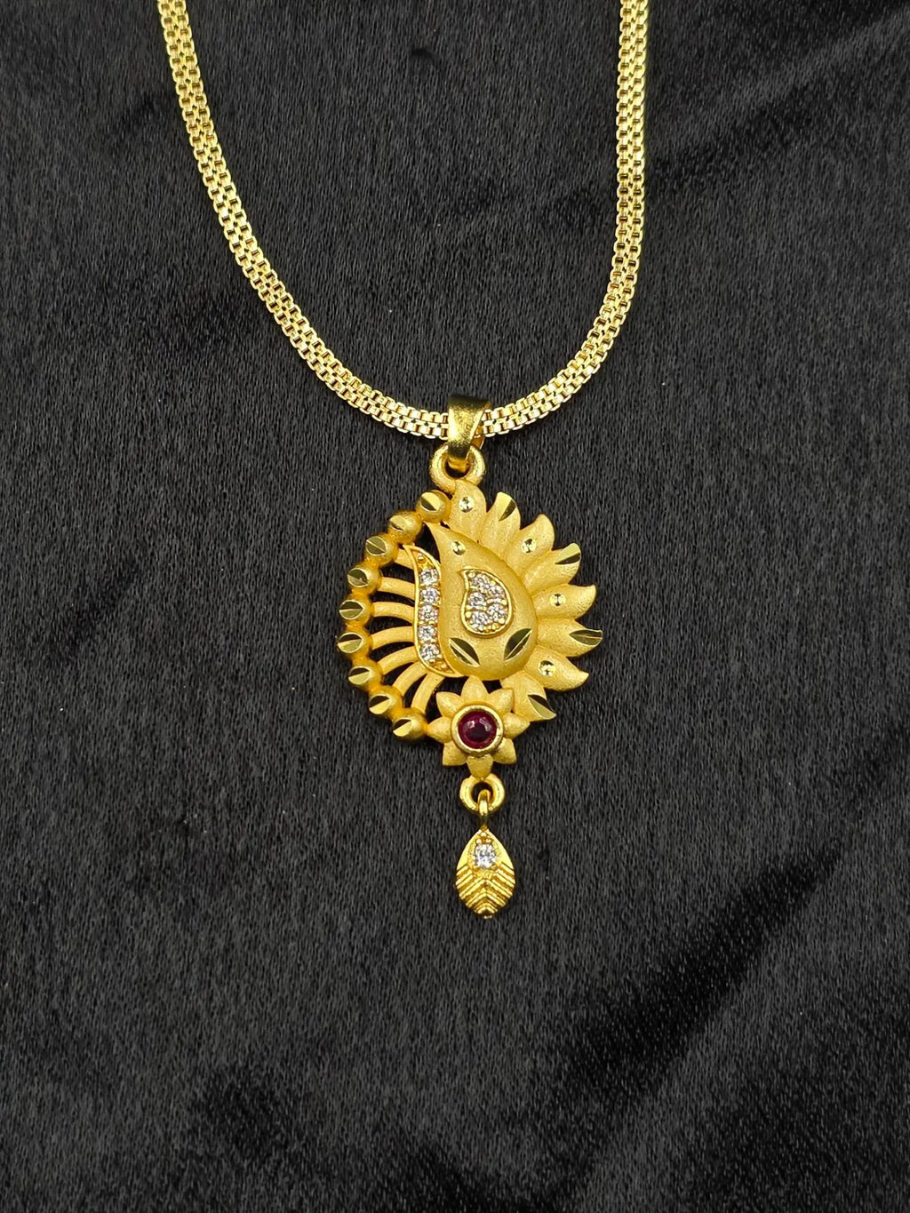 Gold necklace with a decorative pendant on a black fabric background
