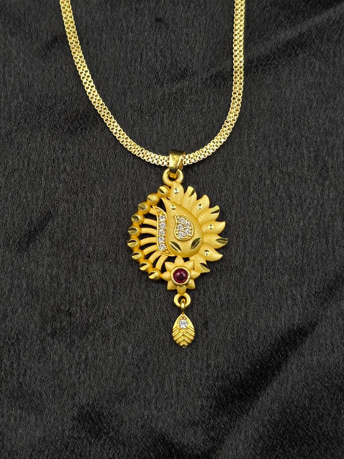 Gold necklace with a decorative pendant on a black fabric background