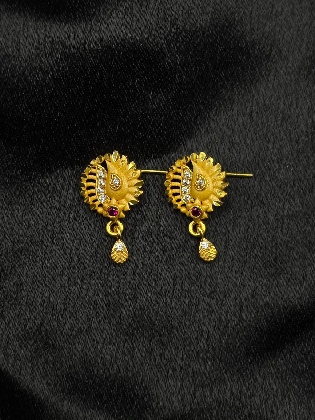 Gold earrings with gemstones on a black background