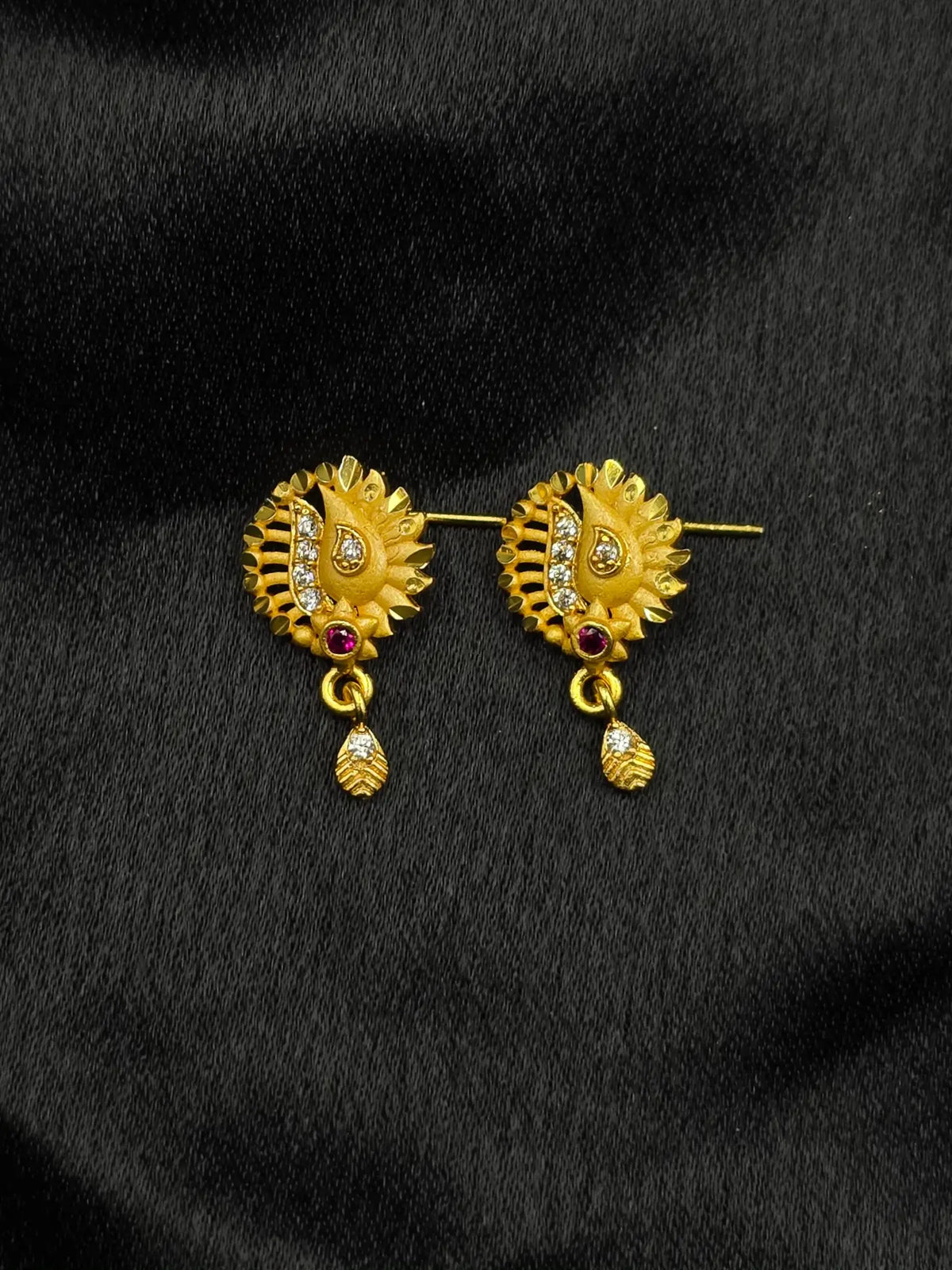 Gold earrings with gemstones on a black background
