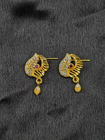 Gold earrings with gemstones on a black fabric background