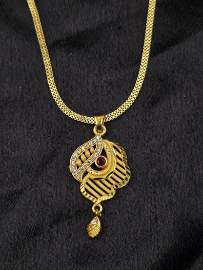 Gold necklace with a pendant featuring a red gemstone on a black background