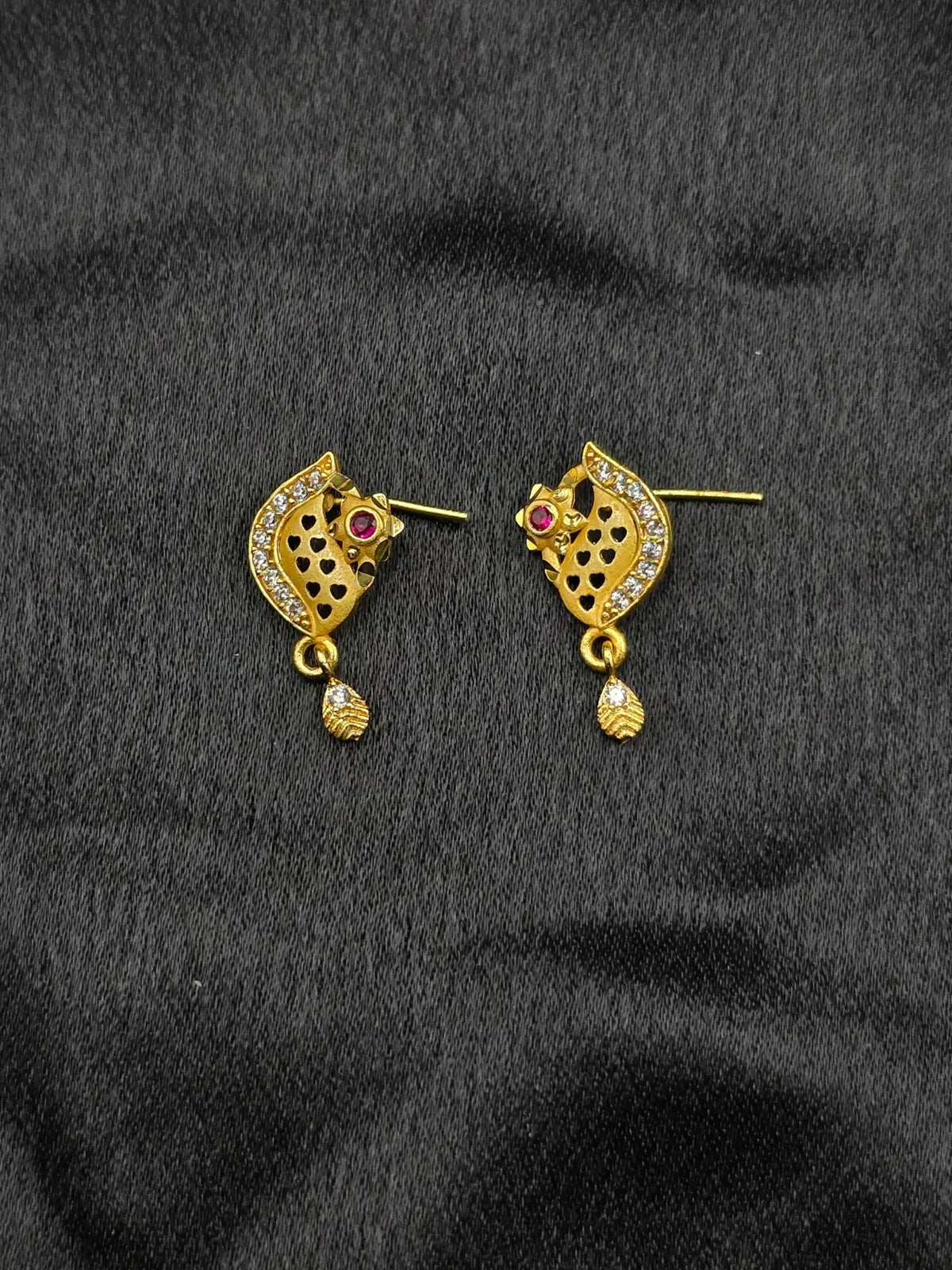 Gold earrings with gemstones on a black fabric background