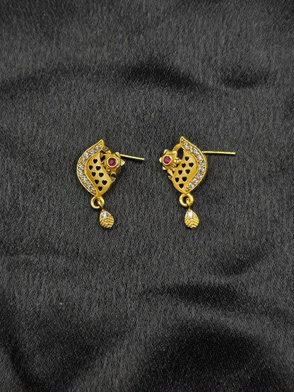 Gold earrings with gemstones on a black fabric background