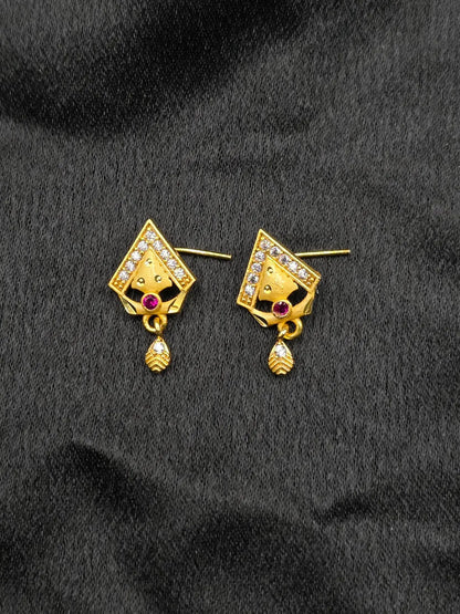 Gold earrings with gemstones on a black fabric background
