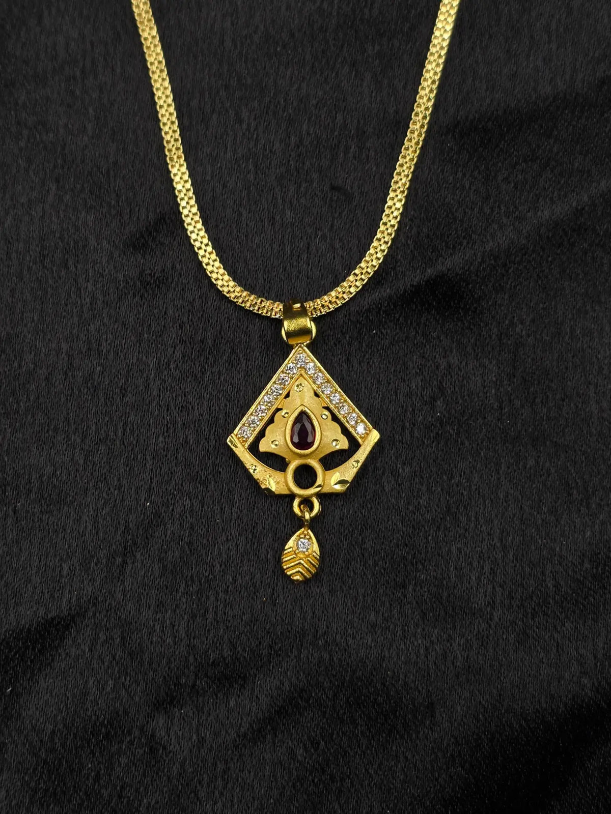 Gold necklace with a diamond-shaped pendant on a black background