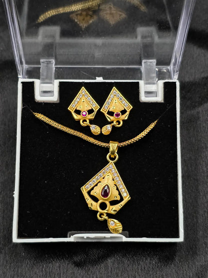 Gold necklace and earrings set in a clear display case on a black background