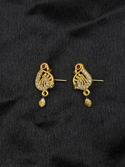 Pair of gold earrings with intricate designs on a black fabric background
