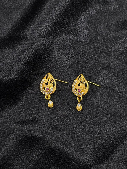 Gold earrings with gemstones on a black fabric background