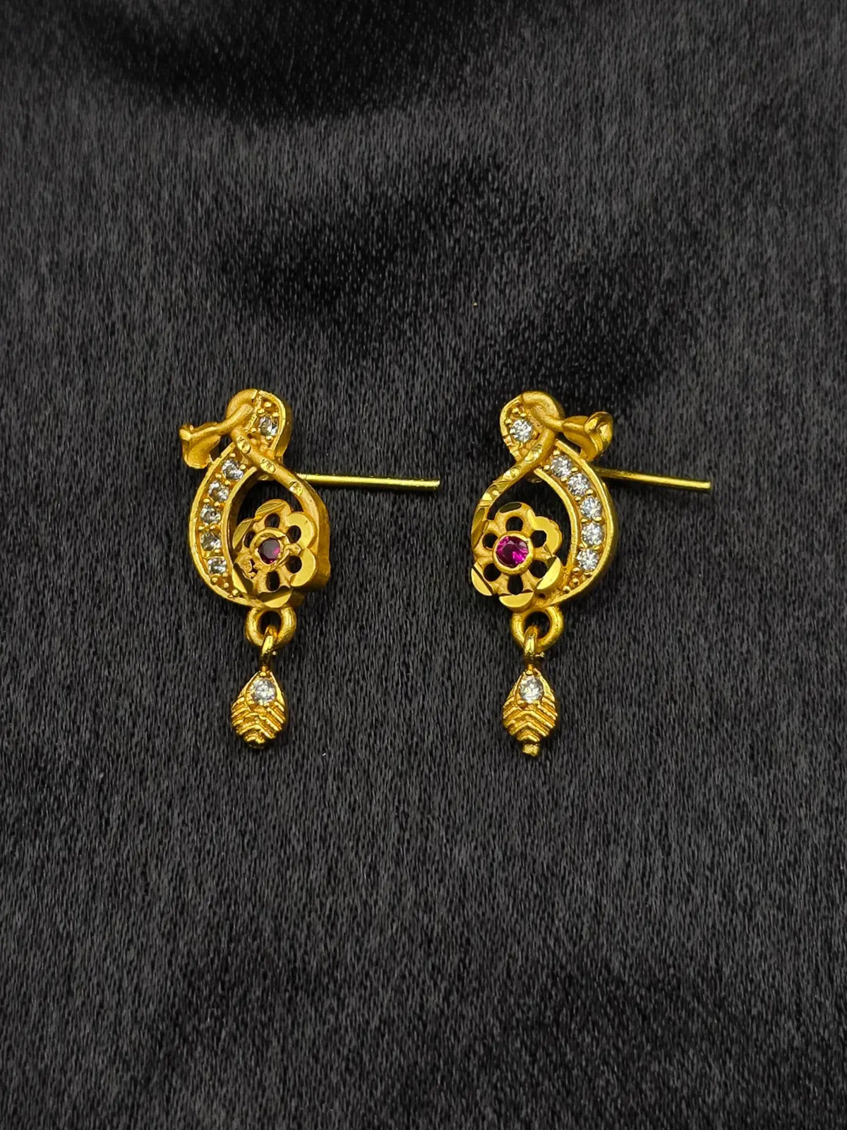 Pair of gold earrings with gemstones on a black background