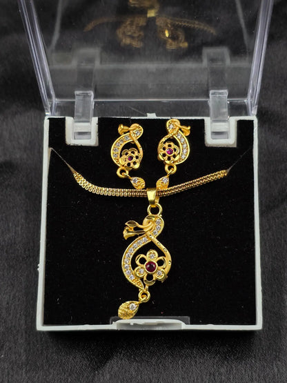 Gold necklace and earrings set on a black cushion with a clear display case.
