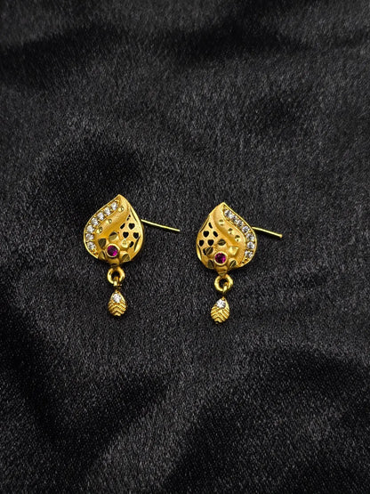 Gold earrings with gemstones on a black fabric background