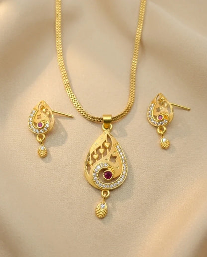 Gold necklace and earrings set on a beige background