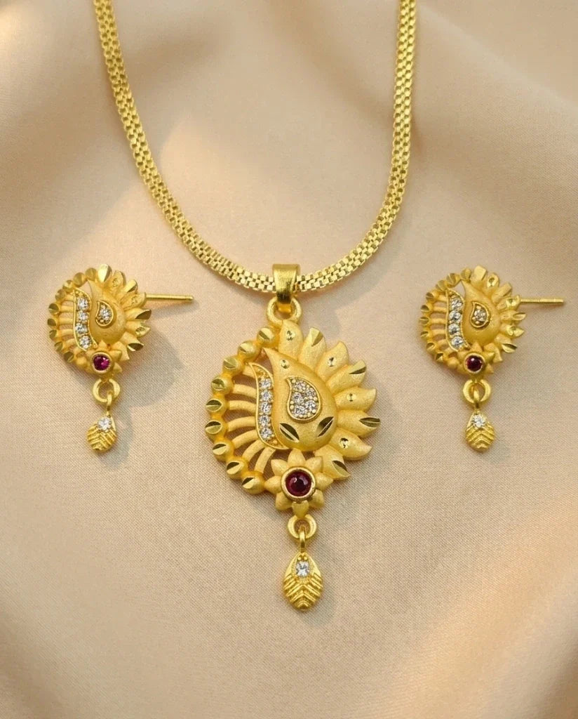 Gold necklace and earrings set on a beige background