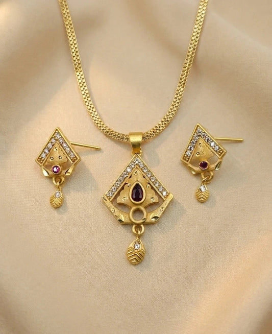 Gold necklace and earrings set on a beige background