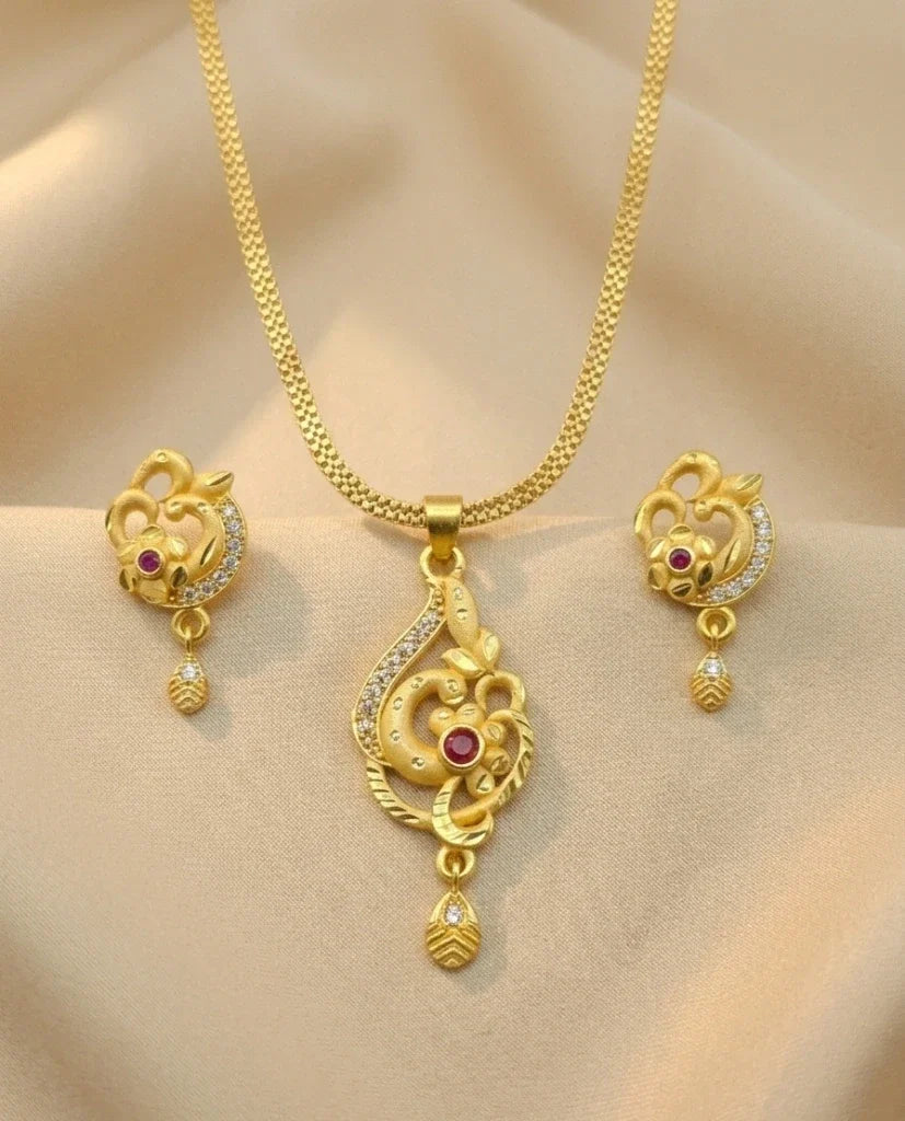 Gold necklace set with pendant and earrings on a beige background