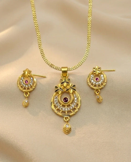 Gold necklace and earrings set on a beige fabric background