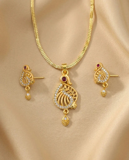 Gold necklace and earrings set on a beige fabric background