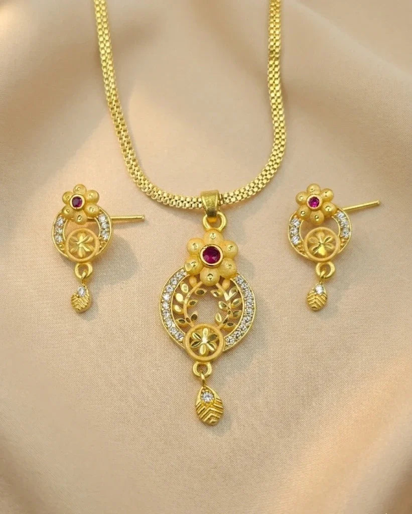 Gold necklace and earrings set on a beige background