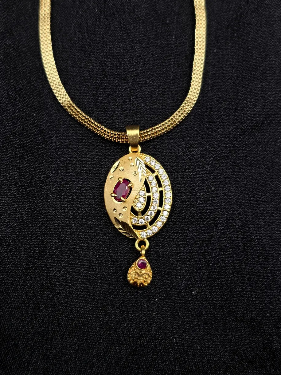 Gold necklace with a pendant featuring red stones on a black background