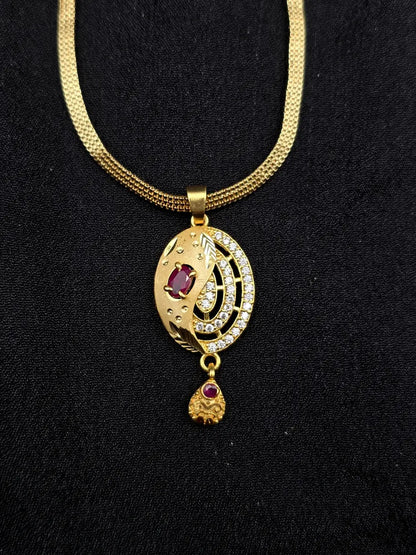 Gold necklace with a pendant featuring red stones on a black background
