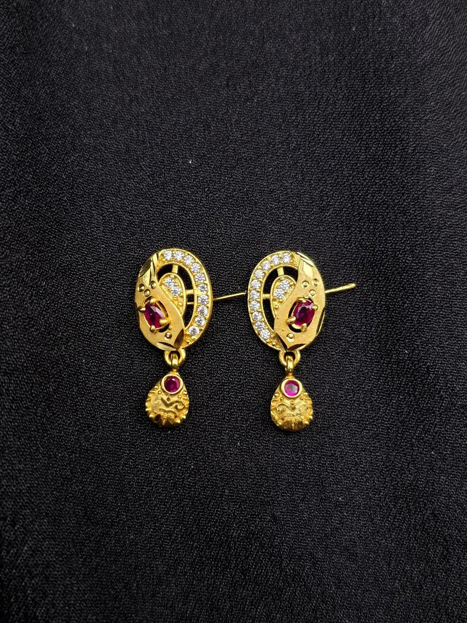 Pair of gold earrings with gemstones on a black background