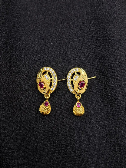 Pair of gold earrings with gemstones on a black background