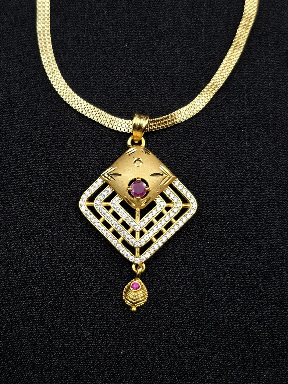 Gold necklace with a diamond-shaped pendant featuring a red gemstone on a black background