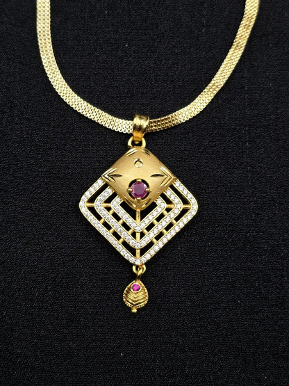 Gold necklace with a diamond-shaped pendant featuring a red gemstone on a black background