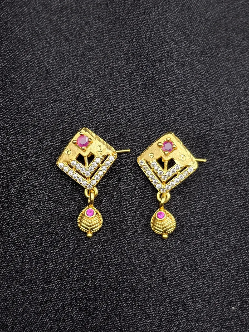 Pair of gold earrings with gemstones on a black background