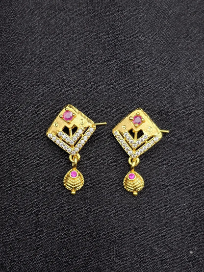 Pair of gold earrings with gemstones on a black background
